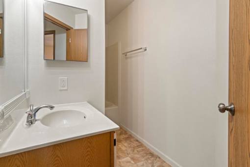 A bathroom with a sink, mirror, and wooden door.