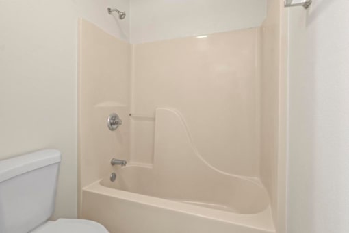 A white toilet sits next to a white bathtub in a bathroom.