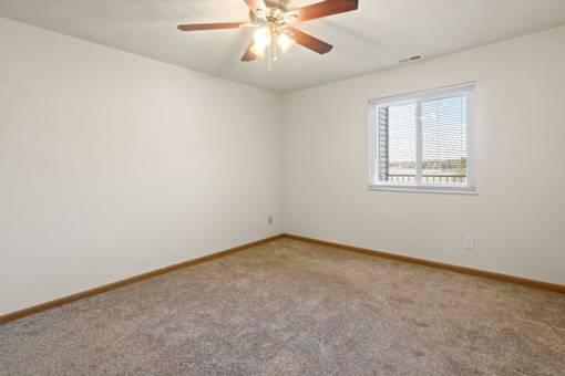 A room with a ceiling fan and a window with blinds.