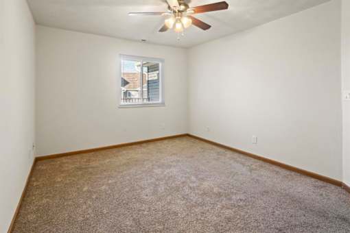 A room with a ceiling fan and a window with blinds.