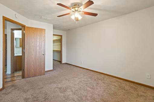 A room with a ceiling fan and carpeted floor.