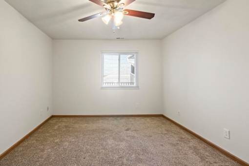 A room with a ceiling fan and a window with blinds.