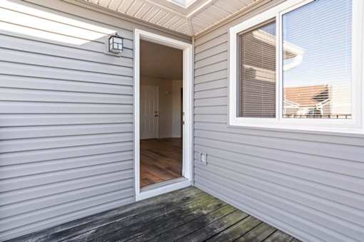 A grey house with a white door and window.