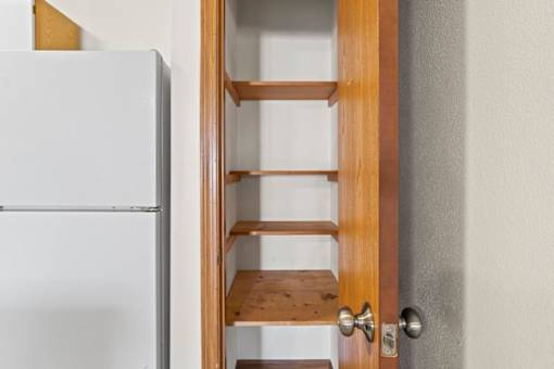 A white refrigerator is next to a wooden door with shelves.