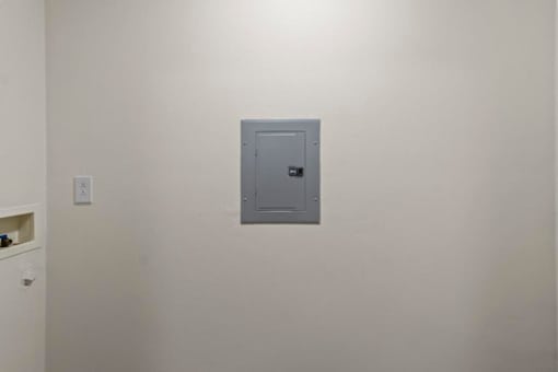 A grey metal safe is on a white wall.