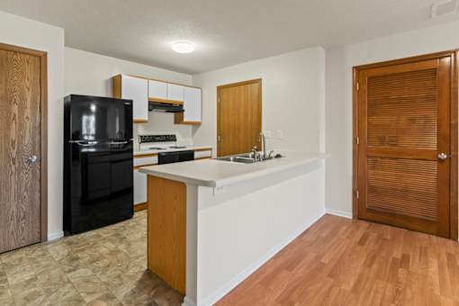 A kitchen with a black fridge and a black microwave.