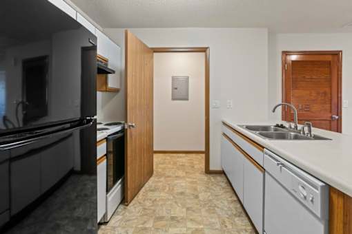 A kitchen with a black refrigerator and white countertops.