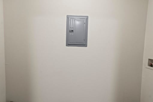 A grey electrical box mounted on a white wall.