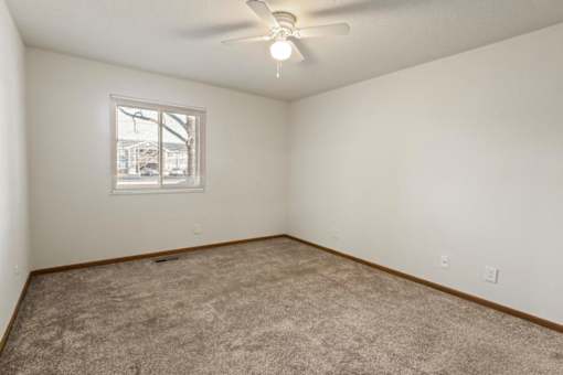 A room with a ceiling fan and a window.