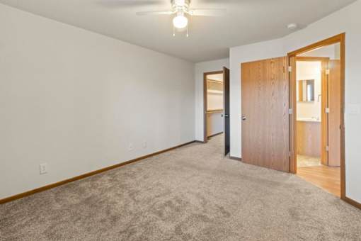 A room with a carpeted floor and a ceiling fan.