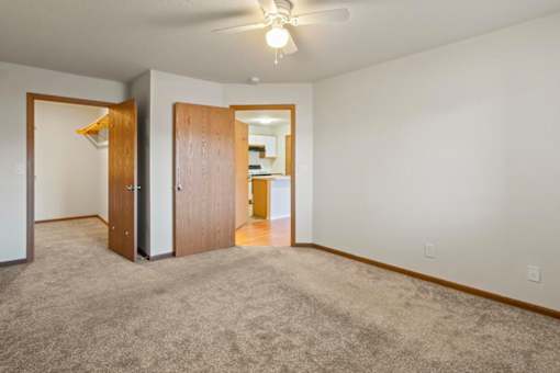 A room with a carpeted floor and a ceiling fan.