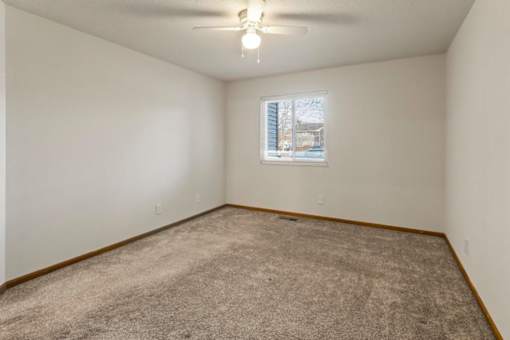 A room with a carpeted floor and a window showing a building outside.