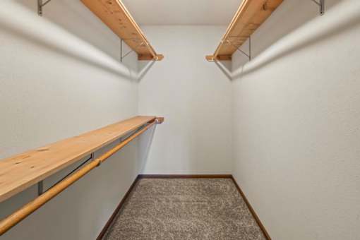 A long, narrow room with a carpeted floor and two wooden shelves.