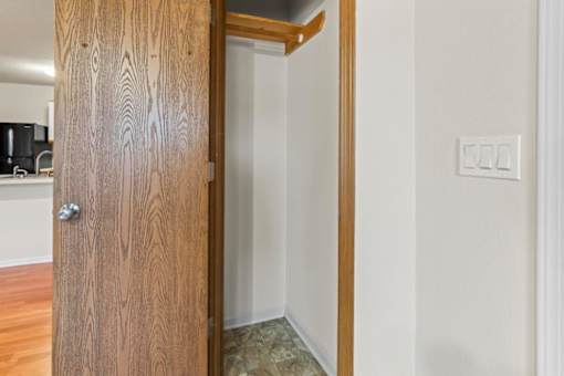 A wooden door is open to a room with a light switch on the wall.