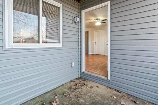 A grey house with a white door and window.