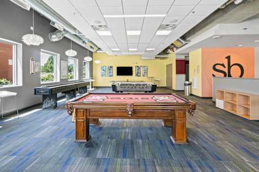A room with a pool table and a bar area.
