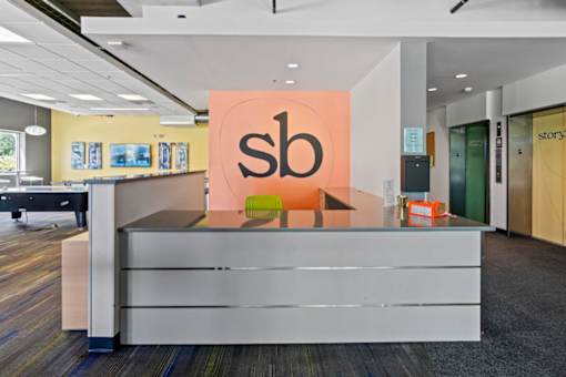 A reception area with a white desk and a sign with the letters "sb" on it.