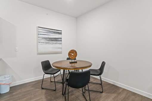 A round wooden table with four chairs around it in a white room.