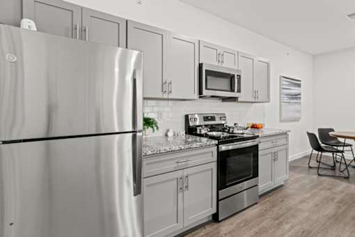 A modern kitchen with a refrigerator, microwave, oven, and a dining table.