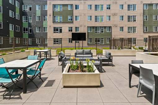 A patio with tables and chairs and a planter in the middle.