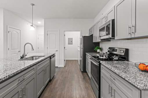 A kitchen with a black fridge and a black stove top.