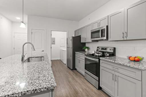 A kitchen with a granite countertop and stainless steel appliances.