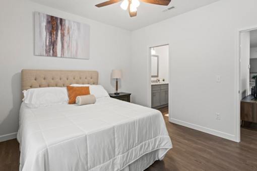 A bedroom with a large bed and a painting on the wall.