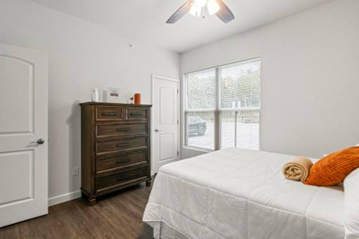 A bedroom with a bed, dresser, and window.