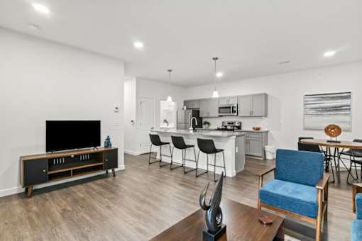 A modern living room with a television, chairs, and a dining area.