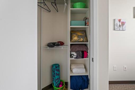 A closet with clothes and a basket on the floor.