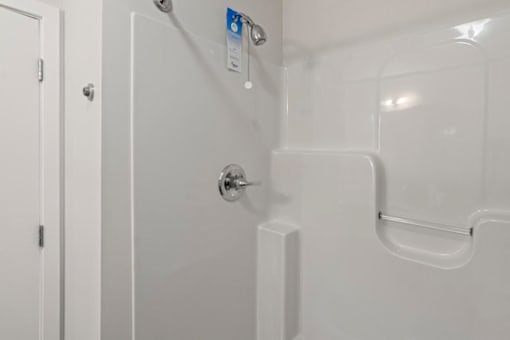 A white door with a handle and a white shower stall with a glass door.