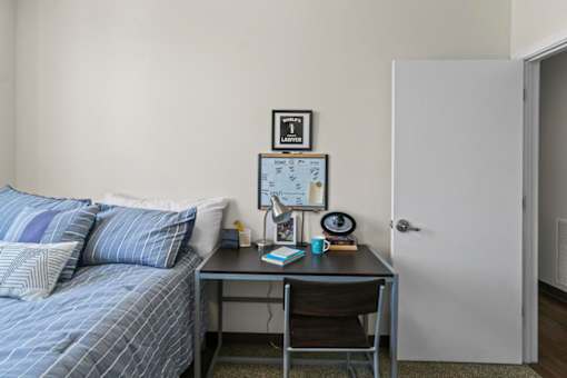A bedroom with a bed, desk, and chair.