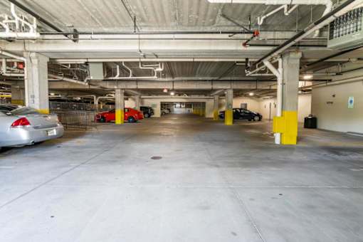 A parking garage with a few cars and yellow poles.