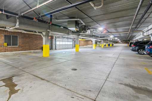 A parking garage with a concrete floor and yellow poles.