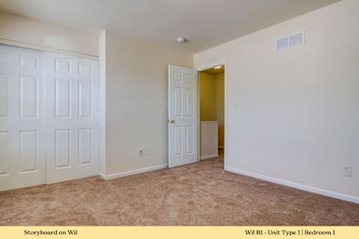 A room with a carpeted floor and a door leading to another room.
