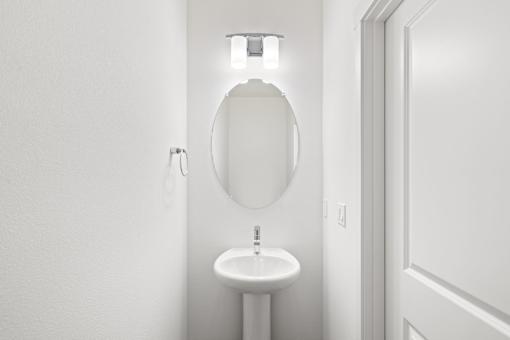 A white bathroom with a toilet, sink and light.