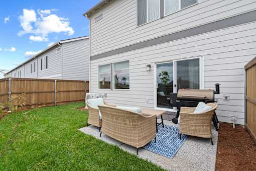 A backyard with a patio set and a house in the background.