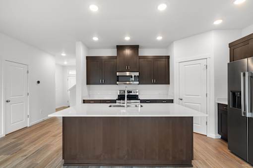 A modern kitchen with dark brown cabinets and a white countertop.