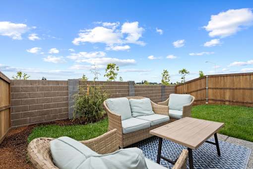 A backyard with a wooden table and two chairs.