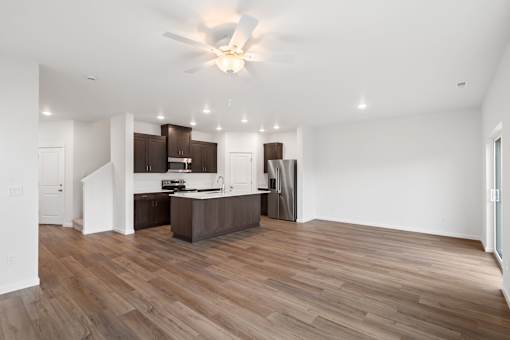 A spacious kitchen with wooden floors and a ceiling fan.