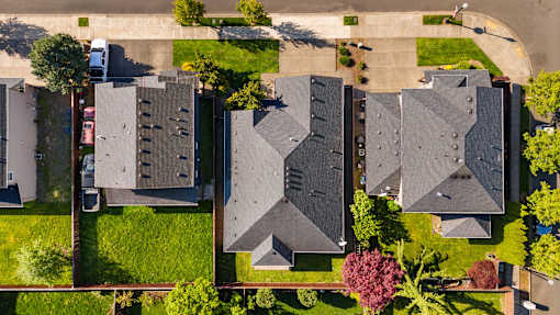 A row of houses with grey roofs and green lawns.