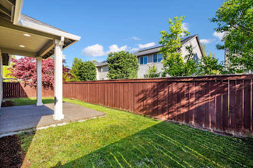 A house with a brown fence and a green lawn.