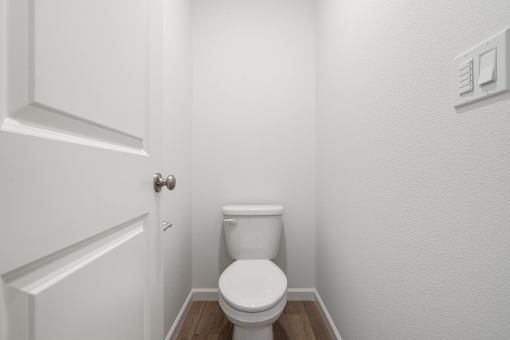 A white toilet in a small bathroom with a door on the left.