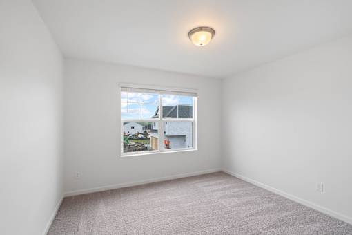 A room with a window showing a view of houses and trees.