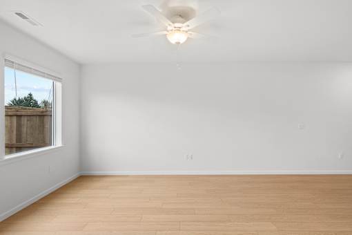 Empty room with a window and a ceiling fan.