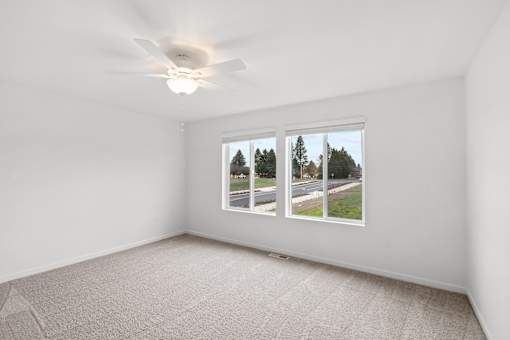 A room with a window showing a view of trees and a road outside.