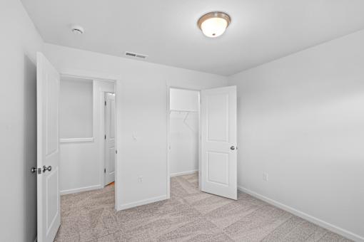 A white room with a carpet floor and a ceiling light.