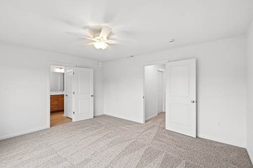 A room with a ceiling fan and carpeted floor.