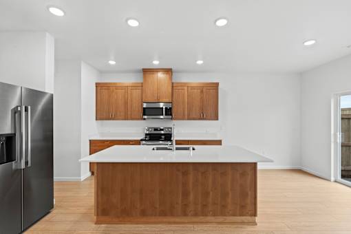 A modern kitchen with wooden cabinets and a stainless steel refrigerator.