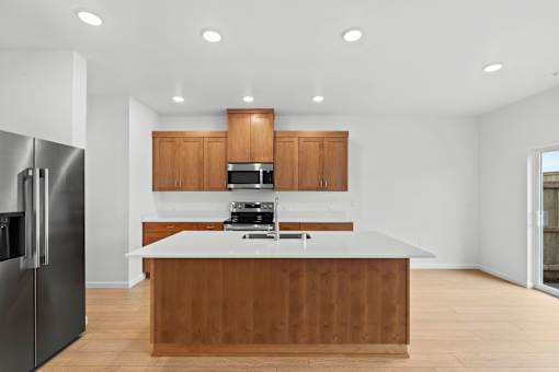 A kitchen with a refrigerator on the left and a counter with a sink and stove.